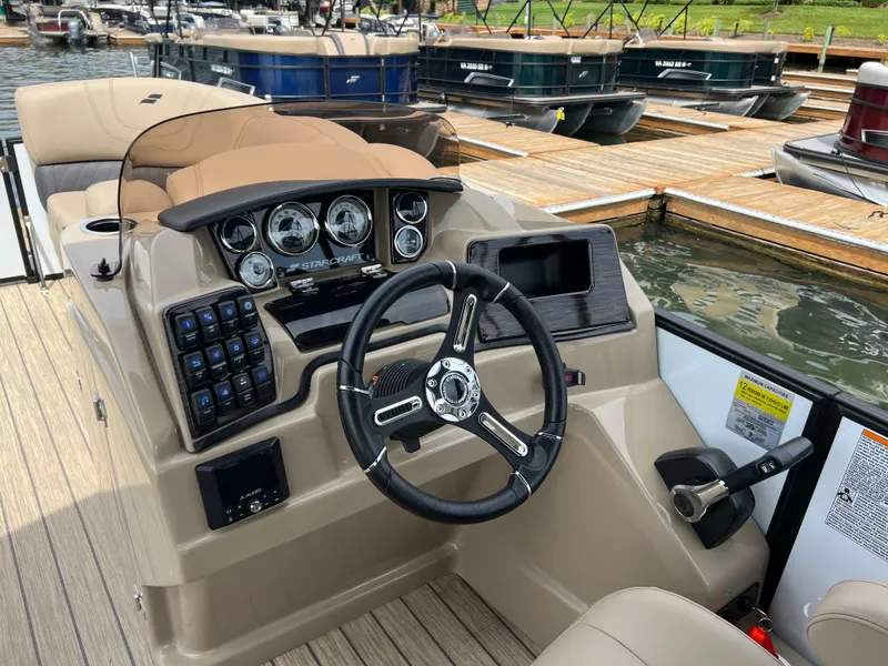 Slide: The Image of 2024 Starcraft SLS 3 boat dashboard with steering wheel and control panel at marina. - 3