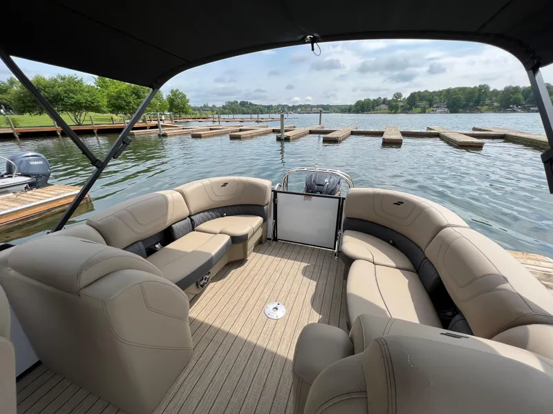 Slide: The Image of 2024 Starcraft SLS 3 pontoon boat with spacious seating at a lakeside dock. - 6
