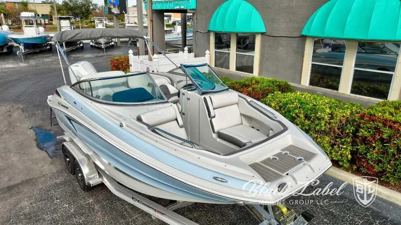 Slide: The Image of 2024 Crownline E240 XS boat on a trailer at a dealership. - 2