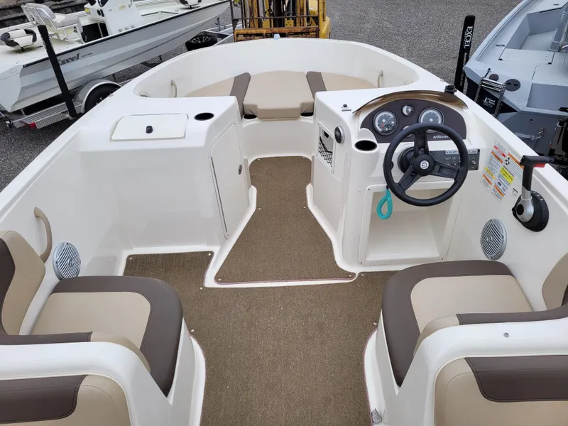 Slide: The Image of 2017 Bayliner Element E21 boat interior with beige and brown seating, steering console, and storage compartments. - 8