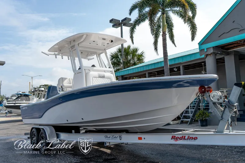 Slide: The Image of 2024 Sea Fox Seafox 251 Bay boat on trailer, displayed outdoors near palm trees. - 2