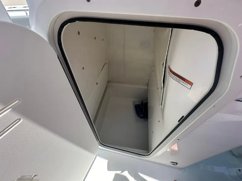 Slide: The Image of 2024 NauticStar 222 OS storage compartment with open door. - 16