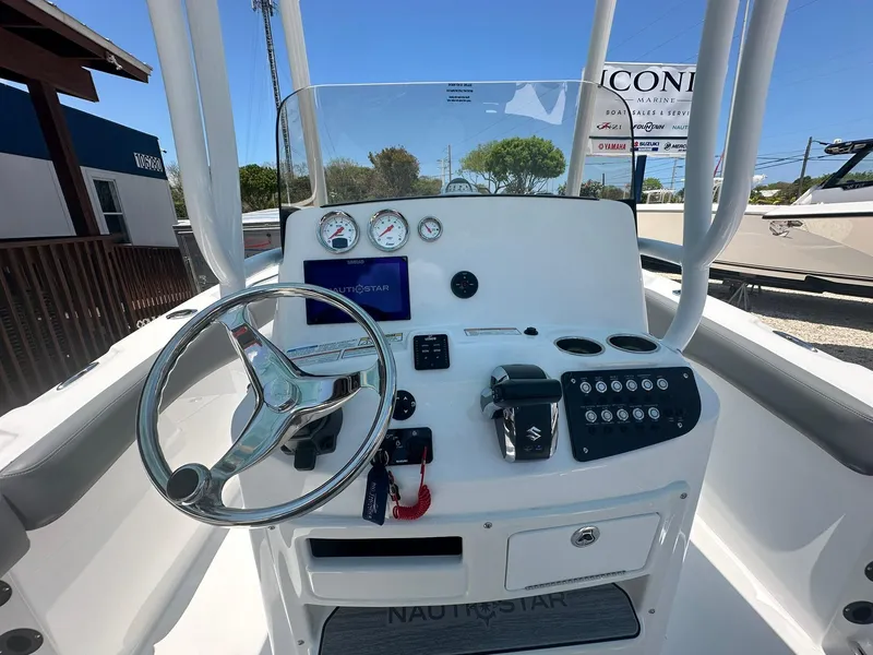 Slide: The Image of 2024 NauticStar 222 OS boat console with steering wheel and control panel. - 2