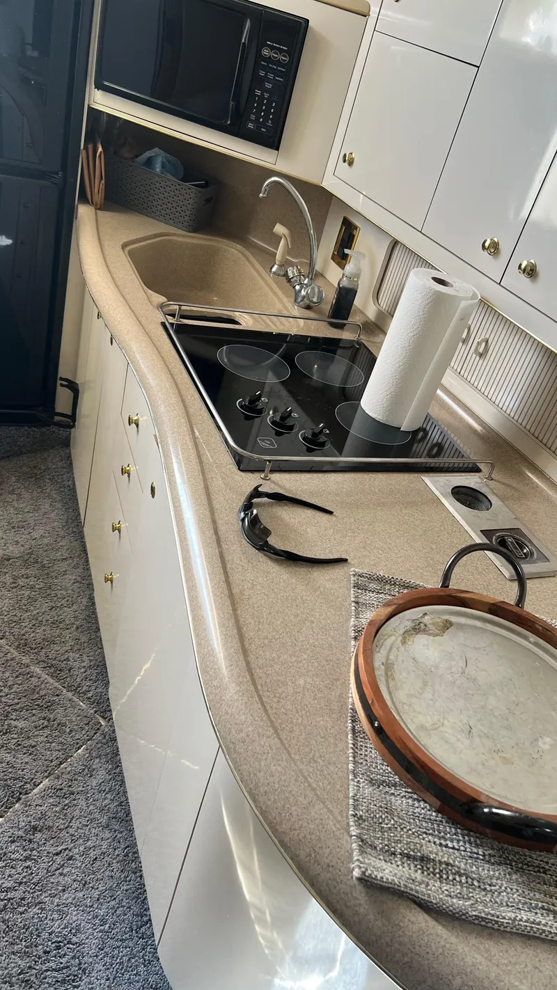 Slide: The Image of 1997 Sea Ray 400 yacht kitchen with sink, stovetop, microwave, and storage cabinets. - 28