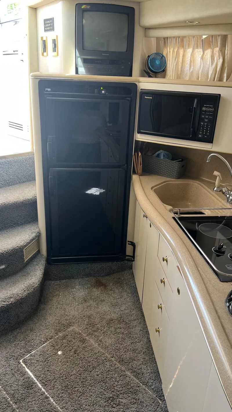 Slide: The Image of 1997 Sea Ray 400 yacht kitchen with microwave, TV, fridge, sink, and stove. - 29