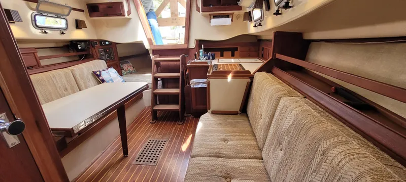 Slide: The Image of Interior of 1986 Island Packet 27 Sloop, featuring cozy seating and wooden finishes. - 10