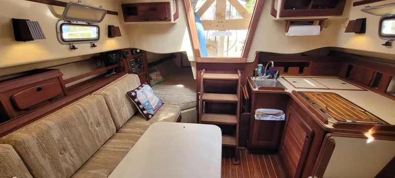 Slide: The Image of Interior of 1986 Island Packet 27 Sloop, featuring cozy seating and compact kitchen area. - 12