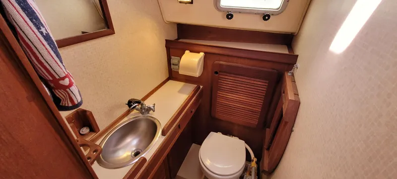 Slide: The Image of 1986 Island Packet 27 Sloop bathroom with sink, toilet, and wooden cabinetry. - 18