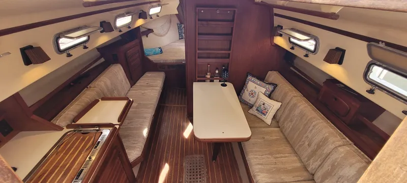 Slide: The Image of Interior of 1986 Island Packet 27 Sloop, featuring cozy seating and wooden finishes. - 2