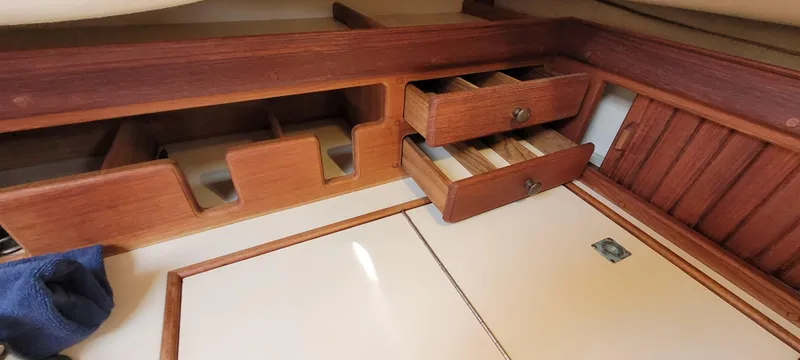 Slide: The Image of Interior of 1986 Island Packet 27 Sloop with wooden storage compartments and drawers. - 26