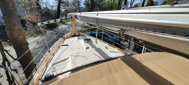 Slide: The Image of 1986 Island Packet 27 Sloop sailboat deck view, mast and rigging visible, surrounded by trees. - 28
