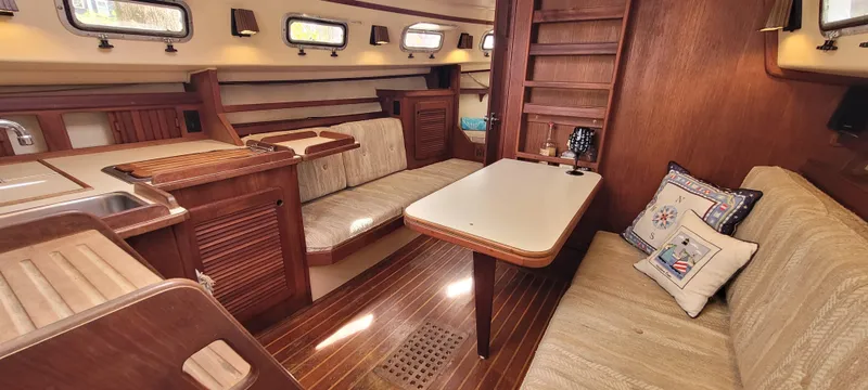 Slide: The Image of Interior of 1986 Island Packet 27 Sloop, featuring cozy seating and wooden finishes. - 3