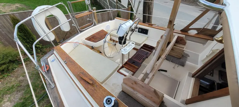Slide: The Image of 1986 Island Packet 27 Sloop cockpit with wooden accents and steering wheel. - 38