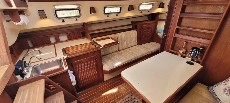 Slide: The Image of Interior of 1986 Island Packet 27 Sloop, featuring cozy seating and wooden cabinetry. - 4