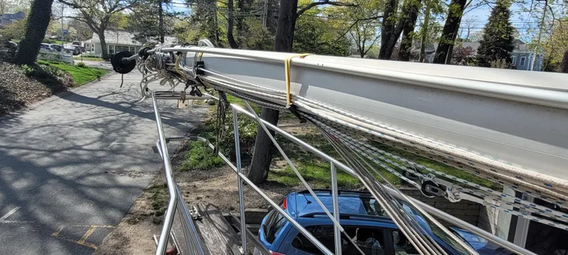 Slide: The Image of 1986 Island Packet 27 Sloop mast on a trailer, parked on a tree-lined street. - 41