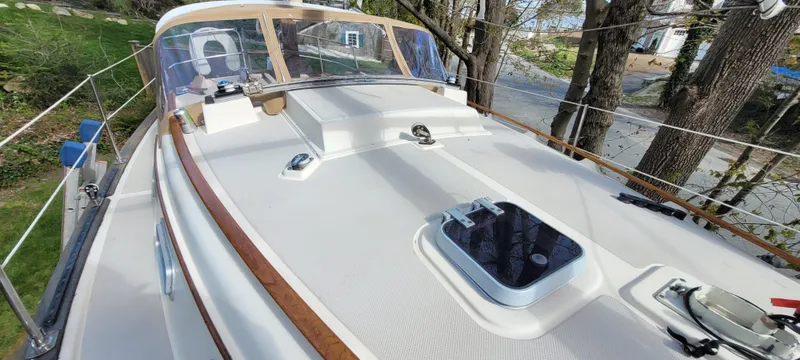 Slide: The Image of 1986 Island Packet 27 Sloop deck with hatches and railing, surrounded by trees. - 44