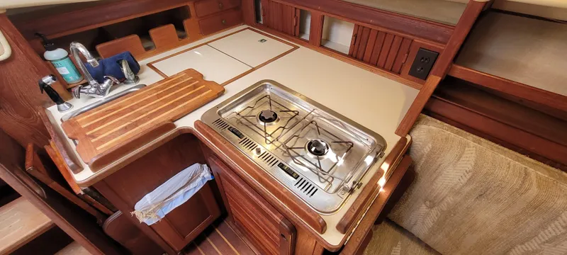 Slide: The Image of Compact kitchen area in a 1986 Island Packet 27 Sloop, featuring a stove and sink. - 6