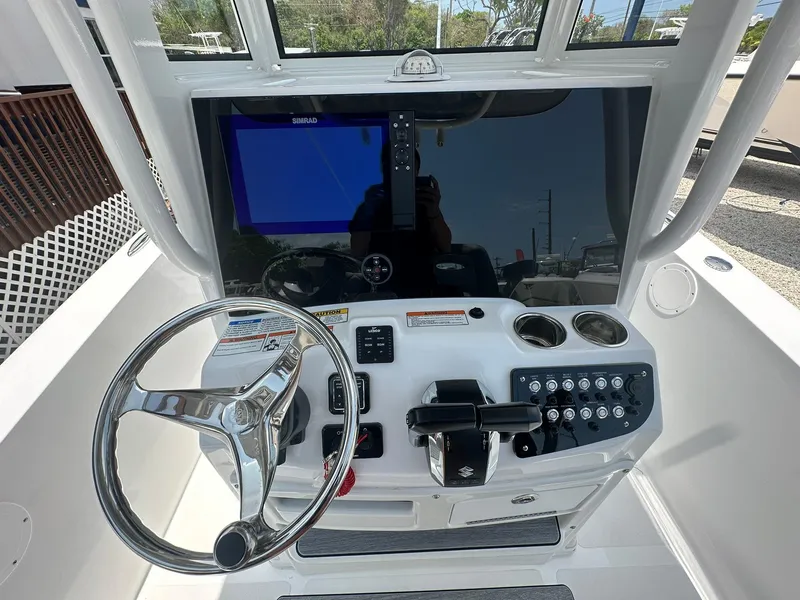 Slide: The Image of 2024 NauticStar 252 boat dashboard with steering wheel, controls, and navigation screen. - 2