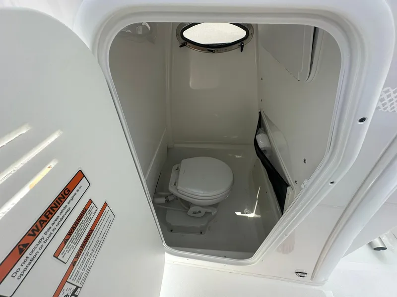 Slide: The Image of 2024 NauticStar 251 boat interior with a compact marine toilet. - 17