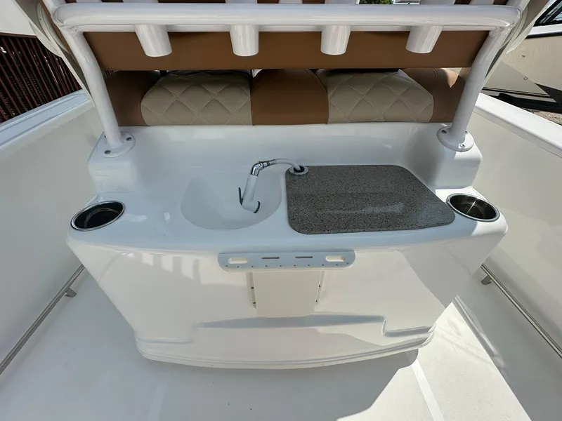 Slide: The Image of 2024 NauticStar 251 boat interior with sink, cutting board, and cup holders. - 19