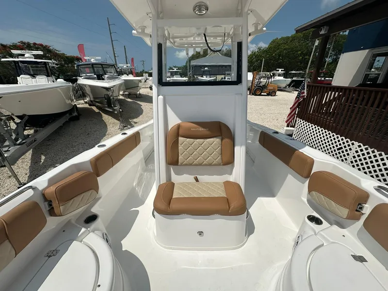 Slide: The Image of 2024 NauticStar 251 boat interior with tan and white seating, docked at a marina. - 7