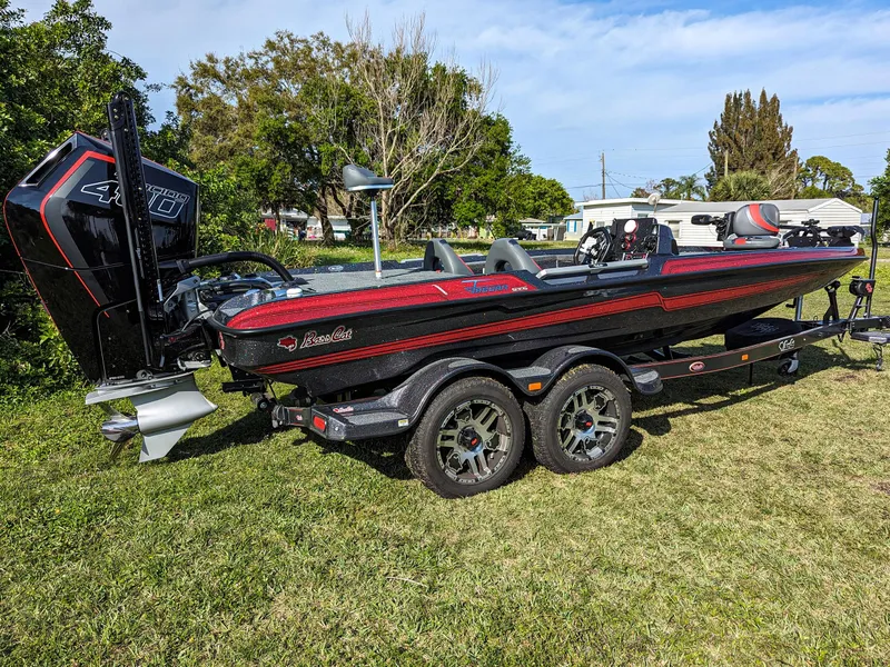 Slide: The Image of 2025 Bass Cat Jaguar boat on a trailer, parked on grass with trees in the background. - 3