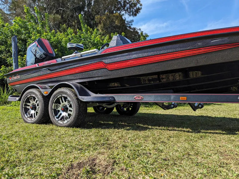 Slide: The Image of 2025 Bass Cat Jaguar boat on a grassy area with a dual-axle trailer. - 5