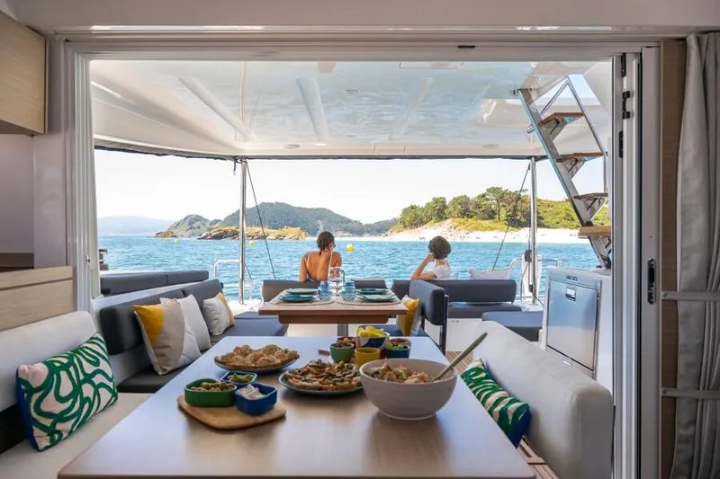 Slide: The Image of Luxurious Lagoon 43 yacht interior with ocean view, dining setup, and scenic backdrop, 2025 model. - 9