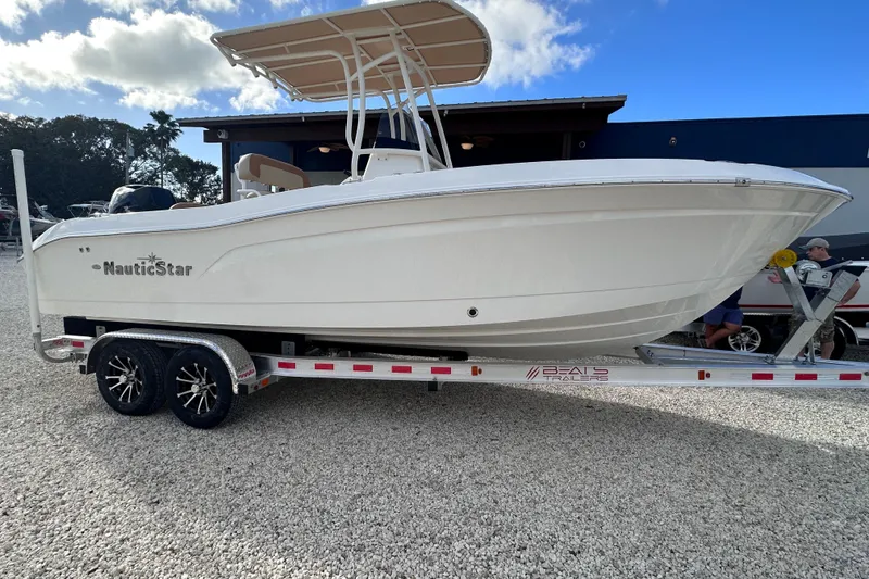 Slide: The Image of 2024 NauticStar 222 boat on trailer, displayed outdoors under a partly cloudy sky. - 1