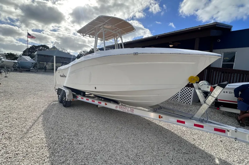 Slide: The Image of 2024 NauticStar 222 boat on trailer, parked outdoors under a partly cloudy sky. - 2