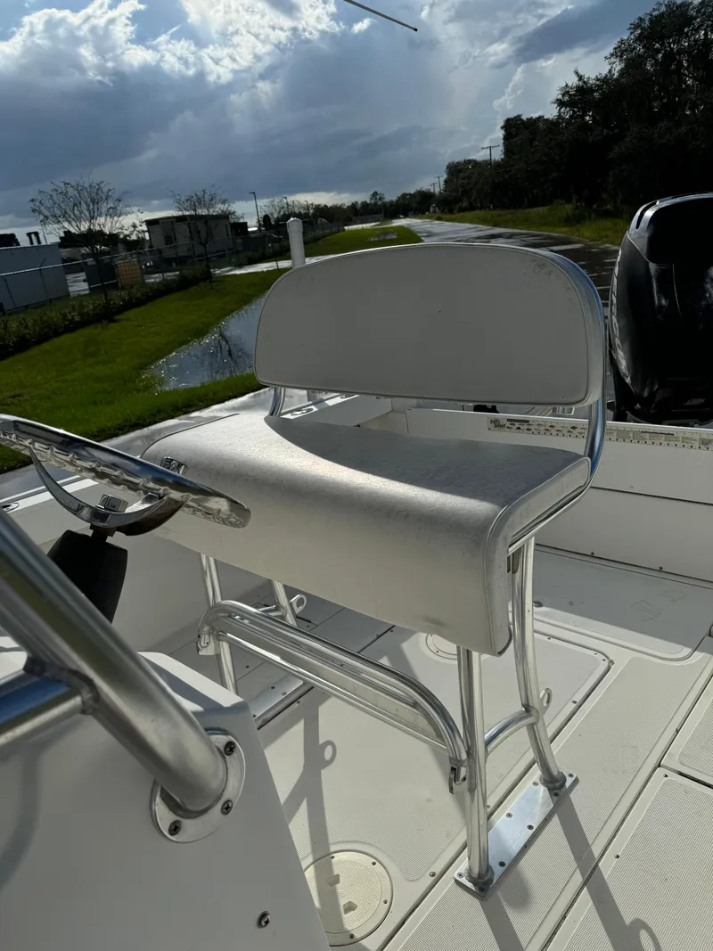 Slide: The Image of 1989 Pursuit 230 Center Console boat with white seating and steering wheel, under a cloudy sky. - 5