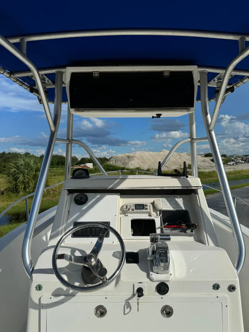 Slide: The Image of 1989 Pursuit 230 Center Console boat with blue canopy and steering wheel. - 7