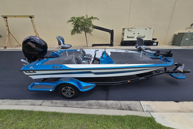Slide: The Image of 2024 Bass Cat Bobcat Vision fishing boat with blue accents, parked outdoors. - 8