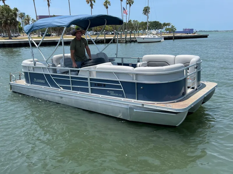 Slide: The Image of 2023 Landau Island Breeze 232 pontoon boat on the water with a blue canopy. - 12