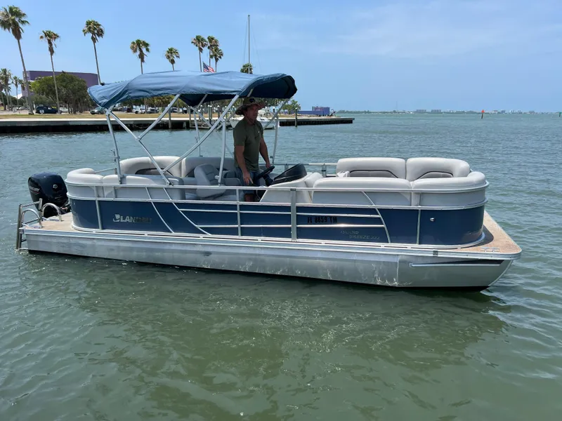 Slide: The Image of 2023 Landau Island Breeze 232 pontoon boat on the water with a person at the helm. - 13