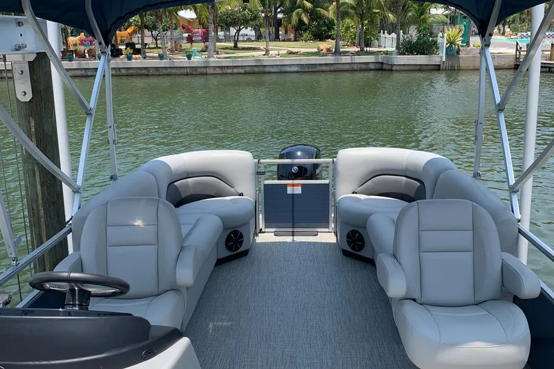 Slide: The Image of 2023 Landau Island Breeze 232 pontoon boat interior with plush seating on a calm waterway. - 17