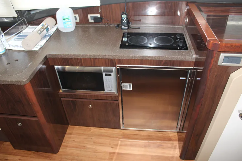 Slide: The Image of Modern kitchen area in 2016 Sea Ray 400 Sundancer yacht with stove, microwave, and fridge. - 29