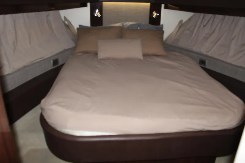 Slide: The Image of Interior cabin of 2016 Sea Ray 400 Sundancer with a cozy bed and pillows. - 48