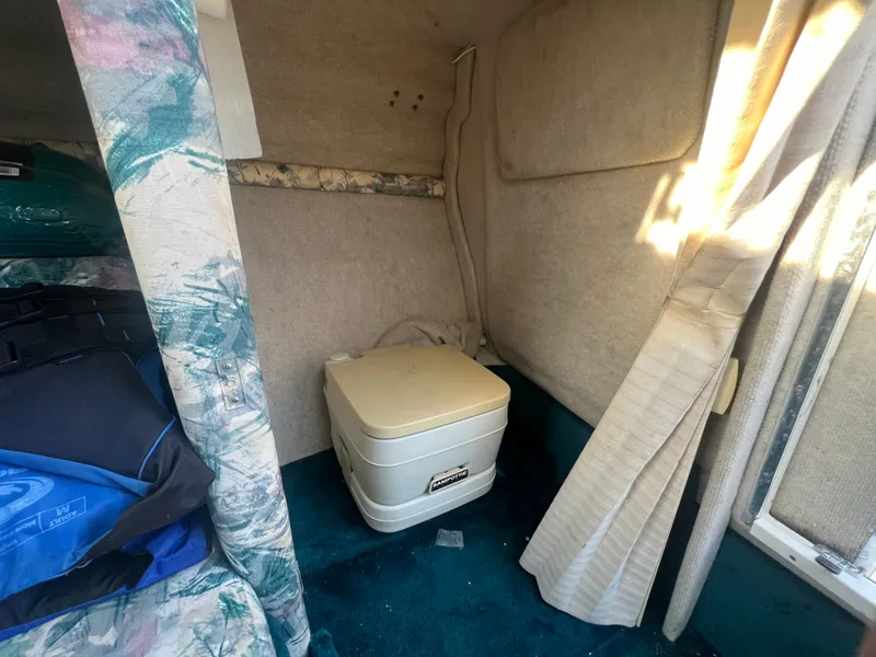Slide: The Image of 1998 Sea Ray 210 Cuddy Cabin interior with portable toilet and floral upholstery. - 16