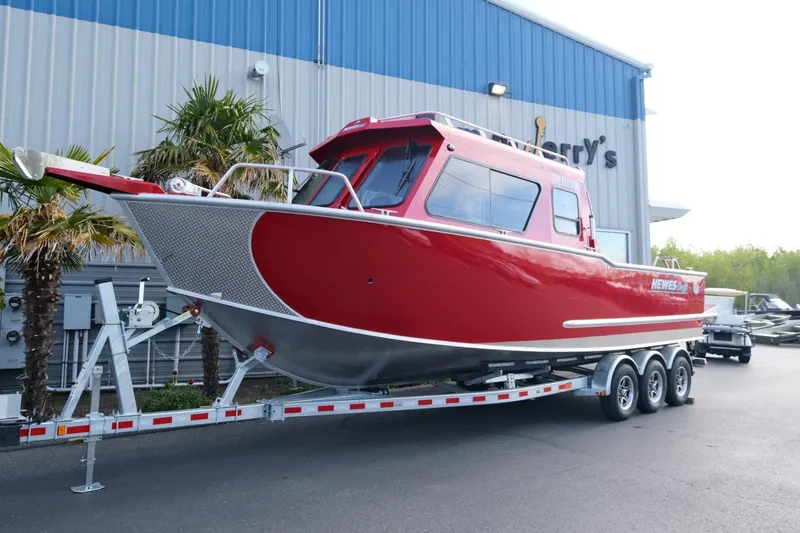The Image of 2024 Hewescraft 270 Alaskan boat in red on a trailer outside a building. - 1