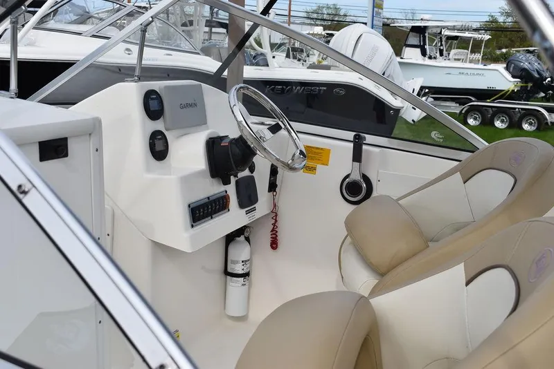 Slide: The Image of 2018 Key West 203DFS boat interior with steering wheel and beige seats. - 15