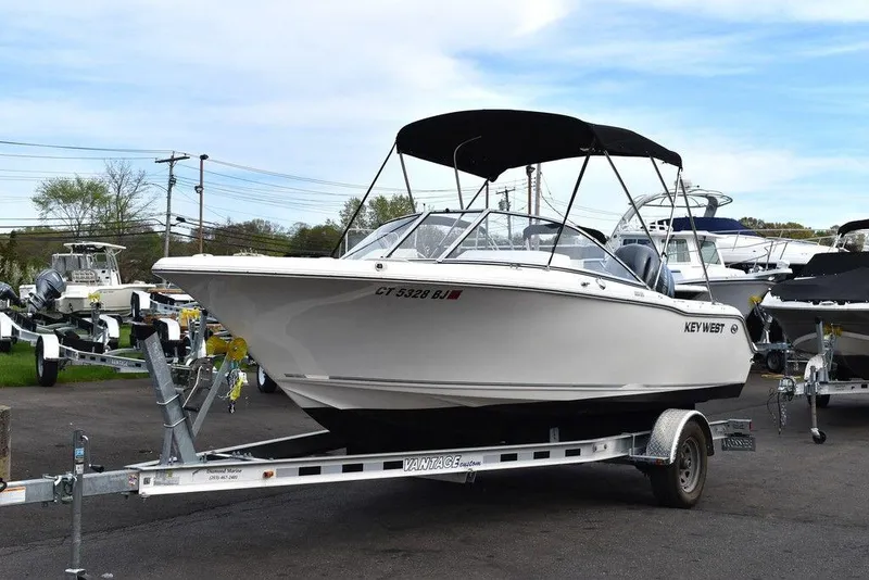Slide: The Image of 2018 Key West 203DFS boat on a trailer with a black canopy. - 2