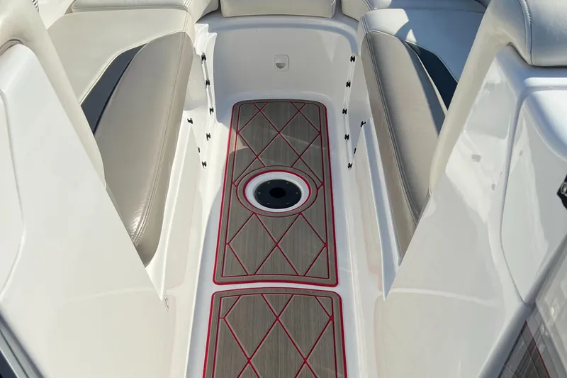 Slide: The Image of 2011 Sea-Doo 230 Wake boat interior with cushioned seating and red-trimmed flooring. - 26