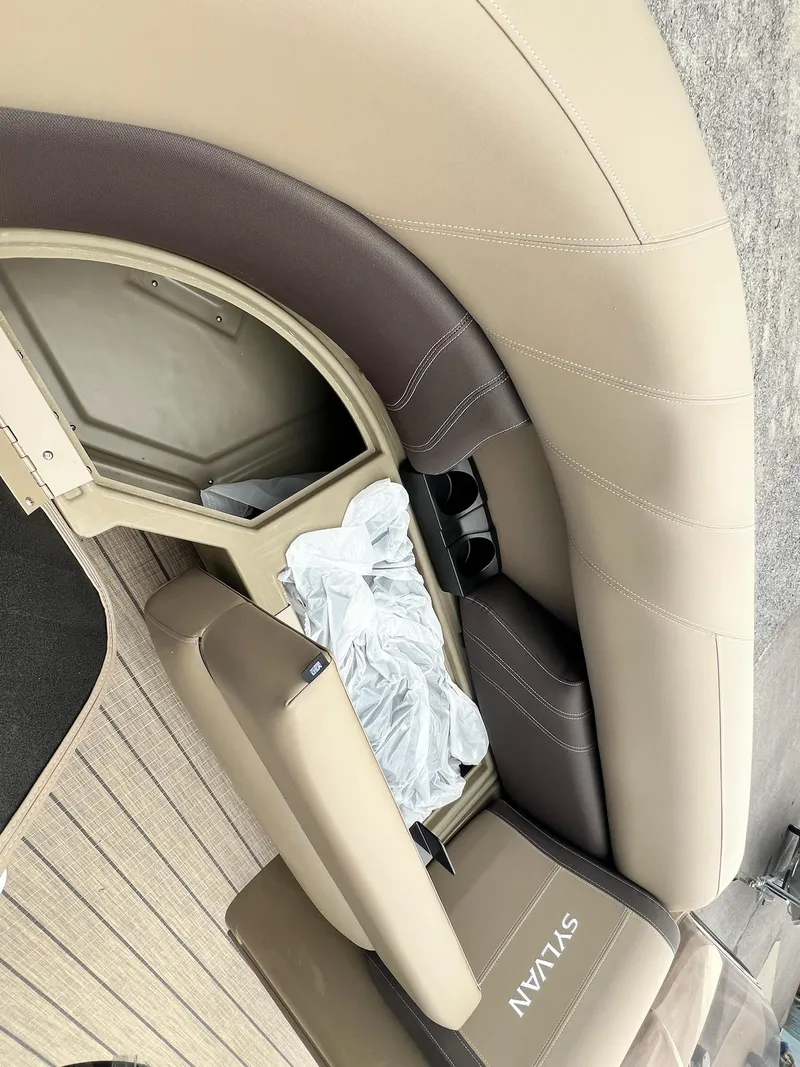 Slide: The Image of 2024 Sylvan 8522 CLZ DH Mirage boat interior with beige and brown seating. - 15