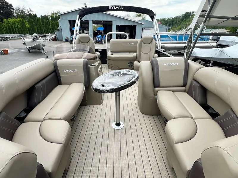 Slide: The Image of 2024 Sylvan 8522 CLZ DH Mirage pontoon boat with beige seating and a central table. - 19