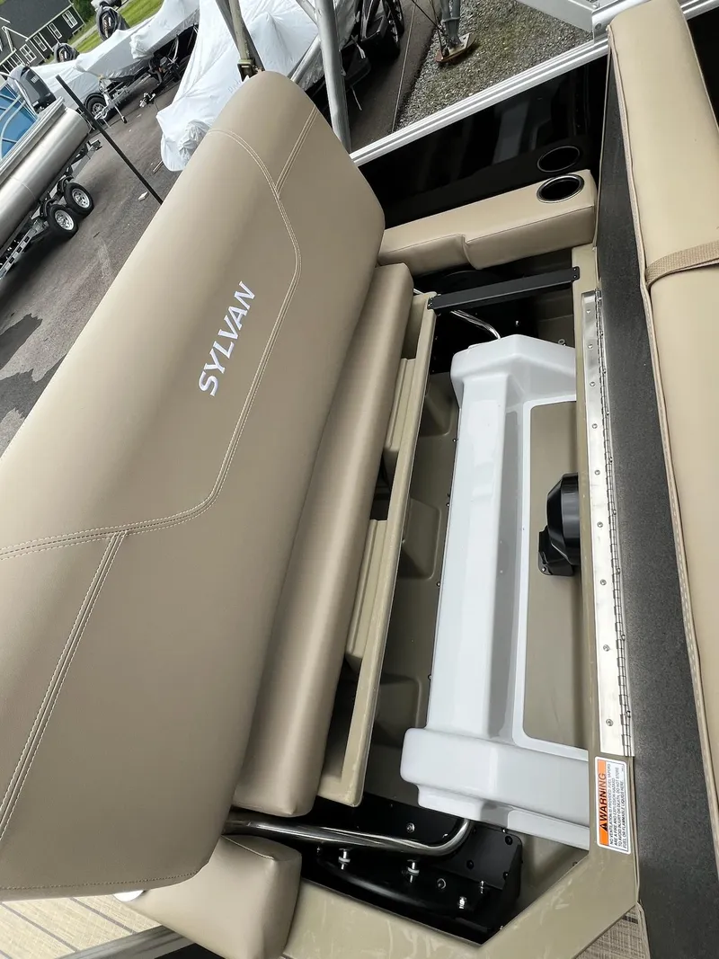 Slide: The Image of 2024 Sylvan 8522 CLZ DH Mirage boat interior with beige seating and storage compartments. - 22