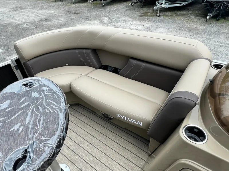 Slide: The Image of 2024 Sylvan 8522 CLZ DH Mirage boat interior with beige and brown seating. - 27