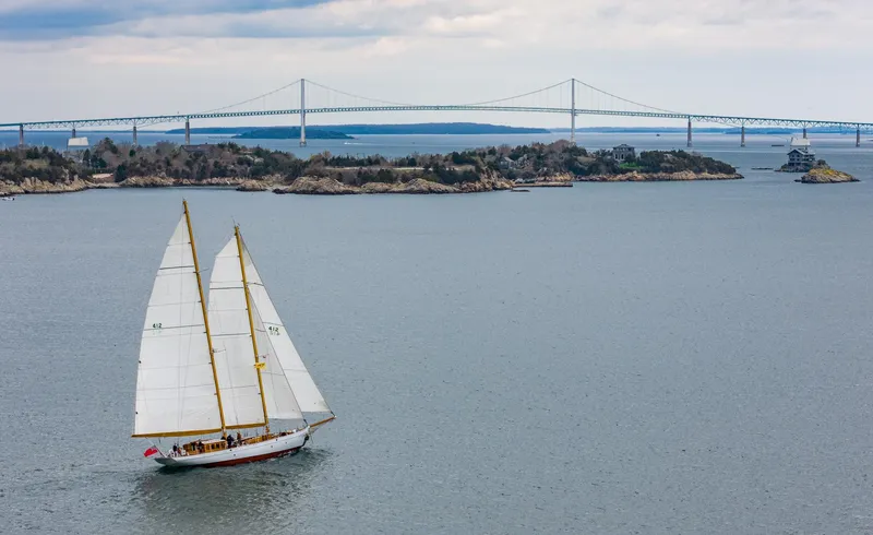 Slide: The Image of 1929 Lyman-Morse Staysail Schooner sailing near a bridge and islands. - 59