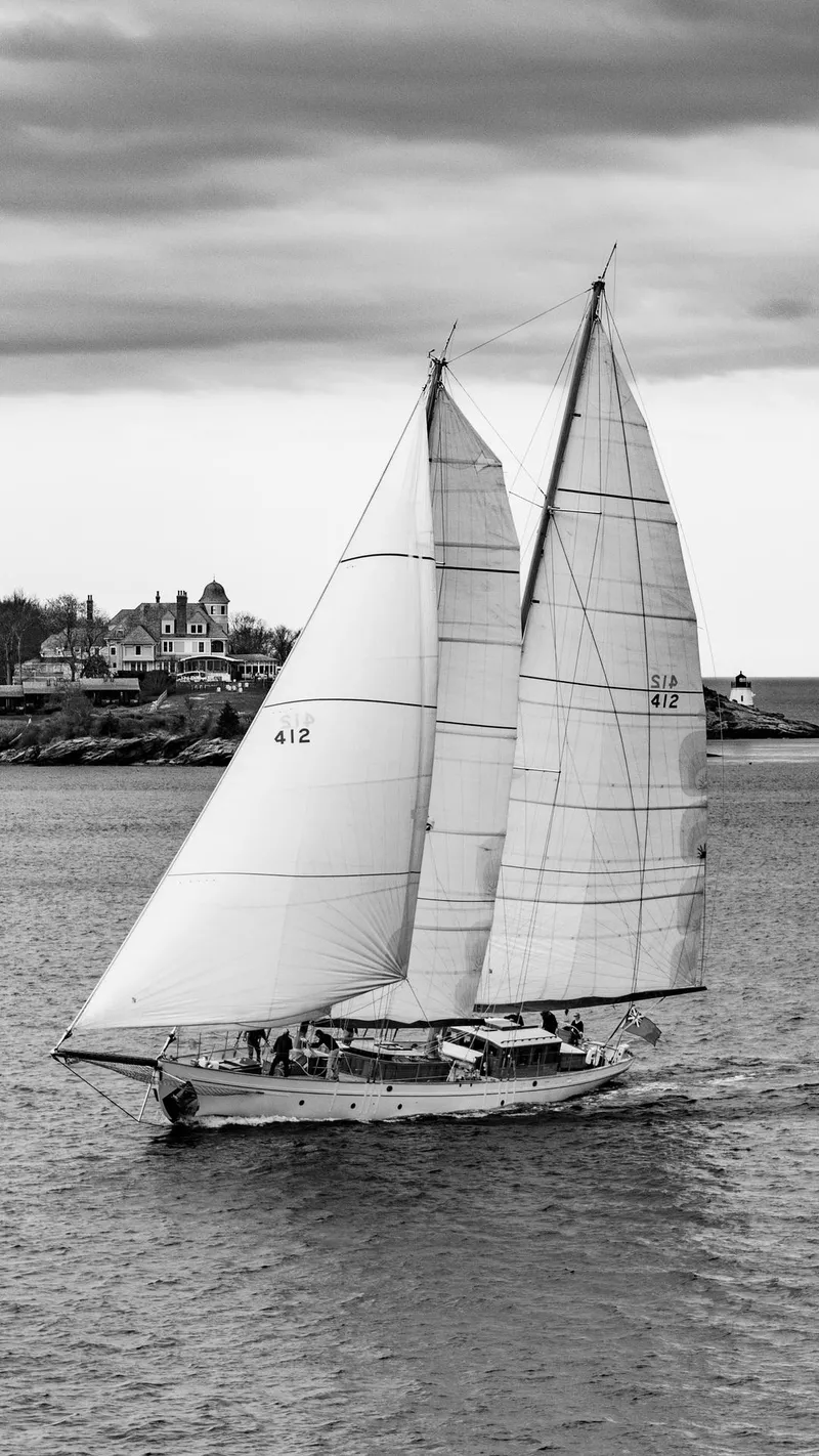 Slide: The Image of Black and white photo of a 1929 Lyman-Morse Staysail Schooner sailing near the coast. - 60