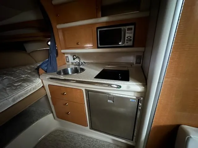 Slide: The Image of 2006 Chaparral 290 Signature boat interior kitchen with sink, stove, microwave, and fridge. - 5